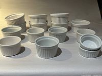 Full view of 15 white ceramic ramekins displayed in groups based on size.