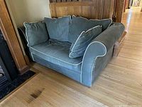 View of green velvet loveseat showing overall condition and included cushions.