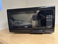 Front view of Salton black microwave oven showing door and digital control keypad.