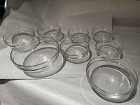 Top view of all 8 clear glass bowls arranged on a white surface showing different sizes from largest to smallest.