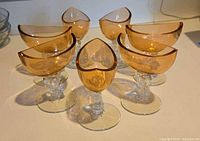 Set of 7 amber luster glass sherbet glasses arranged in a circle, showcasing the unique art glass stems shaped like koi or dolphins.