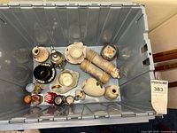 Top view of plastic container holding Merri-bells, metal teapot, ceramic vase, cup, trinket box, and other small items