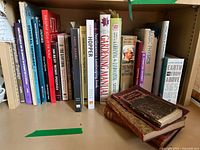Full shelf view of books including antique poetry books with worn covers and a variety of modern hardback and paperback books on physics, topology, gardening, puzzles, and art.