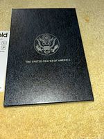Closed black presentation folder with US eagle seal on front