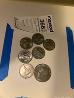 Photo of seven assorted U.S. coins including Eisenhower dollar, Kennedy and Clinton half dollars, and other smaller coins.