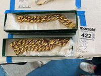 Full view of the 14K gold necklace and bracelet in green boxes with white cushion.