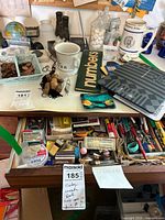 Desk top with two white mugs, globe bank, pennies, wood duck figurine, various mouse pads, and a box of numbers cards.