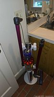 Vacuum and docking stand leaning against wall near sink