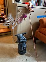 Overall view of the resin cherub, gazing ball, and wind ornaments including butterfly shapes and copper pinwheel