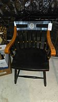 Front view of the Nicholas and Stone Harvard chair showing the Harvard emblem on the backrest, natural wood armrests, and black painted frame.