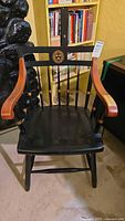 Front view of Windsor-style armchair showing Harvard seal on backrest and curved wood armrests