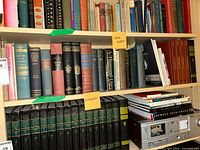 Shelf of assorted hardcover and softcover history books with varied bindings and colors including green, pink, blue, and black.