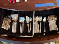 Drawer with organized cutlery separated by type including forks, knives, spoons, butter spreaders, and serving spoons with ornate handles.