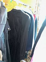 Black coat with suede-like texture hanging with other coats