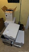 Stack of multiple cardboard boxes containing the office supplies stored in a basement.