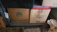 Photo of large boxes including a Gallo Vineyards box and a handle with care box, possibly containing items in the lot
