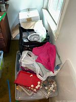 Overview of sewing notions and crafting supplies in bags and plastic containers with fabrics and buttons visible