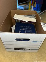 Photo of the open Bankers Box containing multiple stamp books and loose stamps