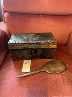 Full view of vintage leather-covered box with metal rivets, handle on top, and the sterling silver hand mirror resting in front