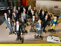 Group of 19 plastic U.S. Presidents figurines arranged in rows on a flat surface, some details of wear visible, each labeled with their last name on a small base.