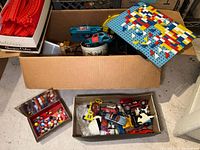 Photo showing box with toy cars, pegboard, and separate boxes containing vintage marbles and scratched toy cars.