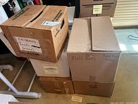 Five cardboard boxes labeled for category such as children's books, math books, baby books, and music books.