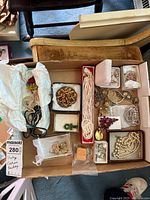 Overall assortment of jewelry in cardboard tray: brooches, necklaces, bracelets, earrings, pendant.