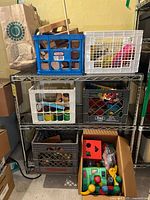 Four crates and a shopping bag on metal shelves with assorted vintage toys including wood puzzle pieces, plastic toys, and blocks