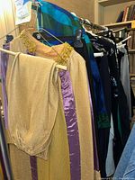 Two-piece vintage women's outfits hanging on rack with various other clothing items visible in background.