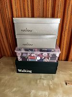 Stacked boxes and containers showing threads and zippers inside, with boxing brands visible.