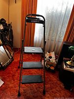 Front view of the 3-step folding ladder showing the ribbed steps and metal frame.