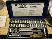 Opened case showing full socket set with tools and sockets arranged in plastic mold inside blue metal case.