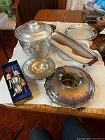Photo showing collection of serving items including the ornate butter dish, ice bucket, serving platters, and wine stoppers on a table.