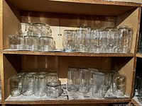 Top left shelves showing rows of various small and medium clear glass canning jars of different shapes.