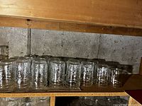 Shelf of clear glass pint sized canning jars turned upside down.
