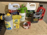 Full lot of garden supplies on table including hose sprayers, cleaning liquids, a pump, and tape.