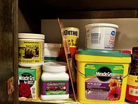 Multiple plant and flower food products on a shelf showing brand names and container types