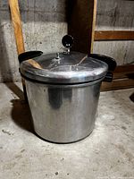Photo of the polished cast aluminum pressure cooker with lid closed, showing black handles and pressure gauge.