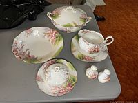 Full set of Royal Albert Blossom Time dishes including the two serving bowls, gravy dish with underplate, butter dish, and salt and pepper shakers, displayed on a gray table.