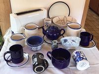 Photo showing overall lot including white Jewjio toaster, blue and white mugs, bowls, pitchers, and teapot.