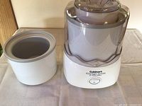 Cuisinart ICE-20 ice cream maker with removable freezing bowl on the left and main motor base unit with transparent lid on the right.