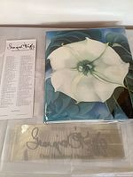 Front cover of the hardcover book with dust jacket showing a detailed white flower painting and two insert cards including the title and signature text.
