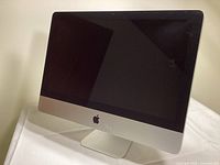 Front view of iMac showing the screen, Apple logo, and aluminum stand.