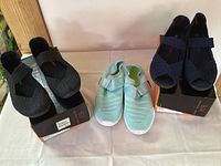 Three pairs of women's shoes on display, size 9. Black and navy Bernie Mev woven shoes with elastic straps, and a sea foam swim shoe with velcro straps.