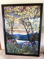 Framed stained glass style print showing floral trees, purple irises, blue lake and mountain background with colorful sky
