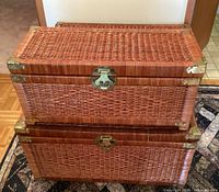 Two wicker trunks stacked, showing the overall condition and brass hardware details on corners and latches.