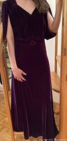 Purple velvet 1930s style dress with V neckline, draped sleeves, and fabric-covered belt.