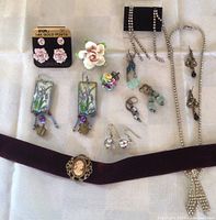 Wide view showing all jewelry items laid on white background including porcelain pins, 14KT gold post earrings, glass bead earrings, floral bead pin, rhinestone earrings, cameo velvet choker, and rhinestone pendant necklace.