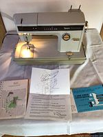 Full view of vintage Sears Kenmore sewing machine with instruction manuals and assembly instructions placed in front
