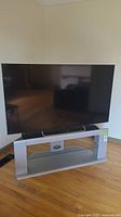 Front view of 60" Sony TV on grey glass stand